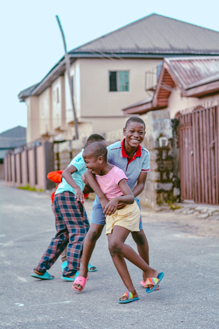 Three kids happily playing in a residential area in Nigeria, capturing the essence of childhood fun.